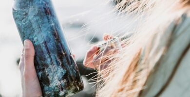 woman in white long sleeve shirt holding blue glass bottle